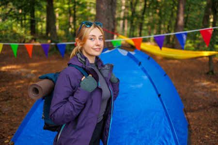 Portrait of a female tourist with a backpack in the forest near a tentの写真素材