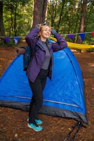 Woman hiker with a backpack in the forest near the tentの写真素材