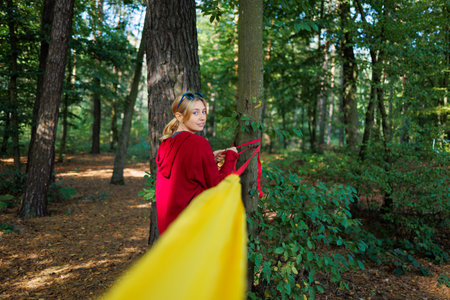 Young woman hooks a hammock to the trees in the forestの写真素材