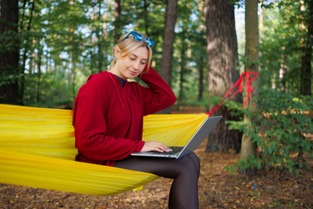 Girl with a laptop on a hammock in the forestの写真素材
