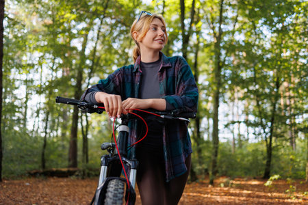 Portrait of a young woman with a bicycle in the forestの写真素材
