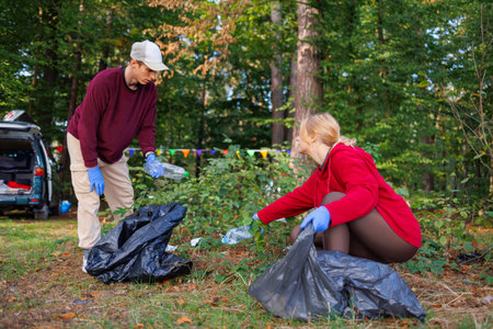 Two young eco volunteers with garbage bags cleaning up trash in the forest. Caring for the environmentの写真素材