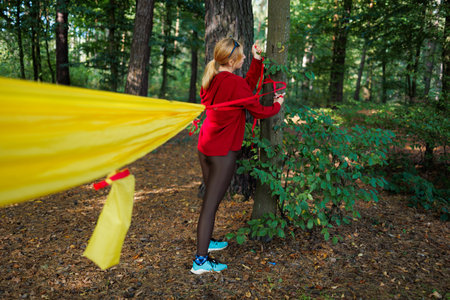 Girl tourist ties a hammock to a tree in the forestの写真素材