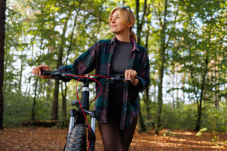 Portrait of a young woman with a bicycle in the forestの写真素材