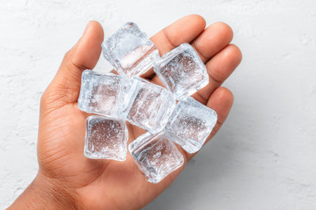 Hand Holding Clear Ice Cubes on White Backgroundの素材