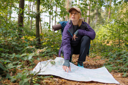 Young woman pointing at map while hiking in the forest