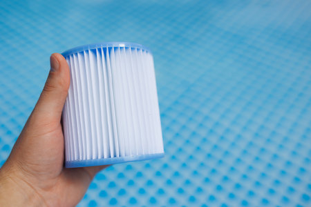 Hand holding clean pool filter cartridge against blue backgroundの写真素材