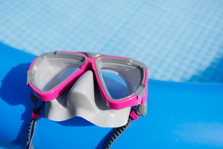 Diving mask with pink frame on edge of inflatable blue swimming poolの写真素材
