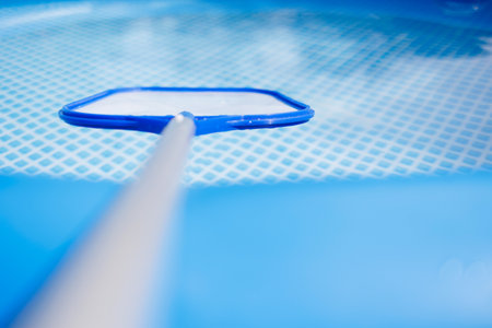 Pool skimmer net in clear blue water for cleaning swimming poolの写真素材