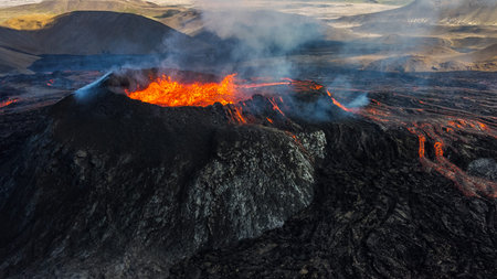 Dramatic volcanic landscape with vibrant red lava flows and textured black rock formations.