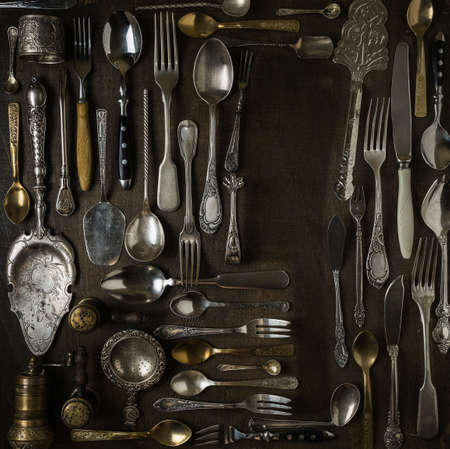 Cutlery, forks, spoons, and knives on dark wooden backgroundの写真素材
