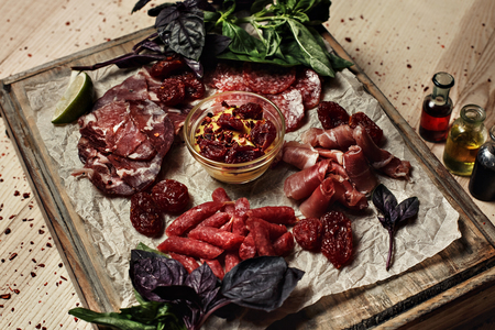 cut meat on wooden board decorated with basilの写真素材