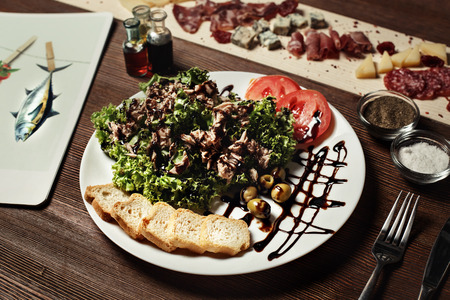 salad of meat, bread, olives and olives, basil. on an old wooden board. Black Zebra cherry tomatoesの写真素材