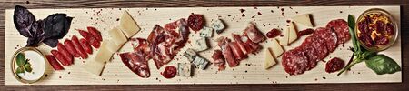 Meat and cheese on a wooden board decorated bazylykom saucesの写真素材