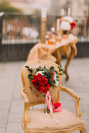 Beautiful wedding bouquet with red flowers on the vintage beige chair.の写真素材