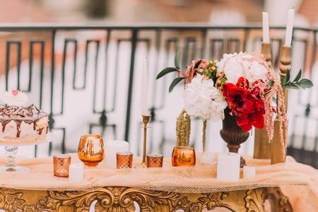 Red flowers and candles in oriental style on the wedding table close up.の写真素材