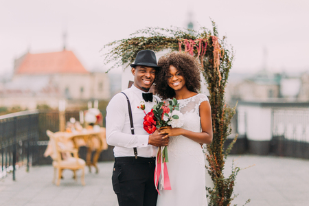 Pretty african wedding couple cheerfully smiling and holding hands.の写真素材