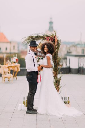Happy african bride and groom posing for camera and smiling on the rooftop.の写真素材