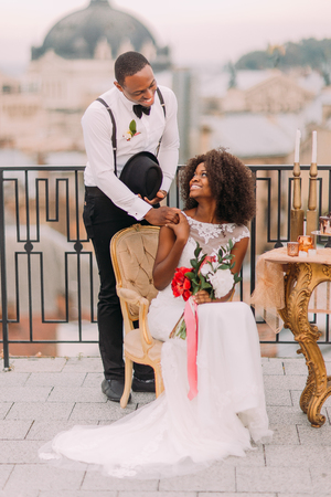 Happy black bride and groom smiling and holding hands on the terrace. Wedding day.の写真素材
