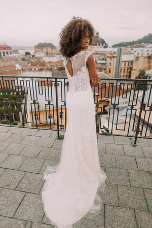 Charming african bride in white lace wedding dress looks over shoulder to the camera.の写真素材
