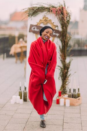 Stylish black girl  in red plaid cheerfully smiling on the rooftop.の写真素材