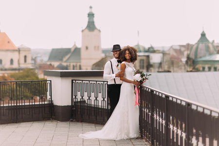 African wedding couple on the rooftop. Amazing european Lviv architecture on background.の写真素材