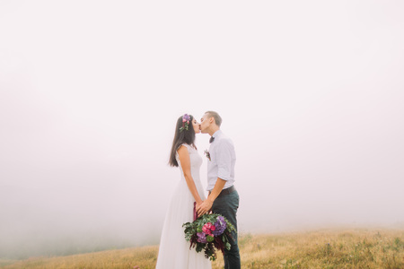 Wedding couple kiss on the field. Mist on backgroundの写真素材