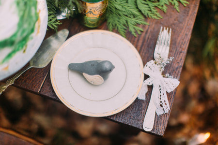 Little cute clay bird on the plate. Vintage table in autumn forest close up.の写真素材