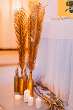 Candles and golden feathers close up. Wedding decorations.の写真素材
