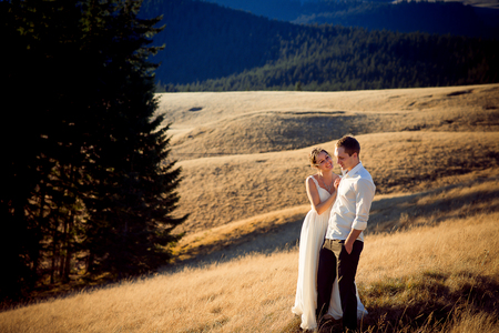 Charming wedding couple standing and smiling on the mountain peak. Honeymoon in Alps.の写真素材