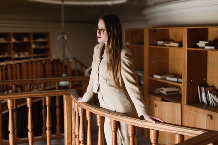 Beautiful young stylish lady on balcony in the vintage library.の写真素材