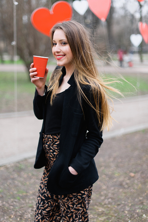 Portrait of young beautiful stylish girl drinking coffee in the park.の写真素材