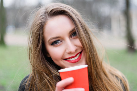 Portrait of young beautiful stylish girl drinking coffee in the park.の写真素材