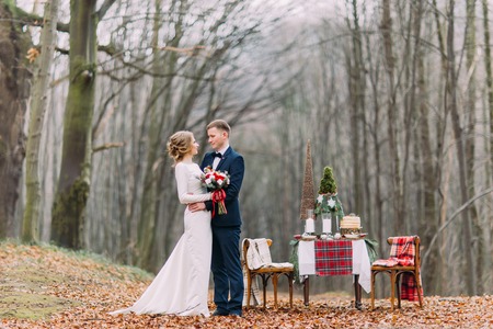Wedding couple near the decorated for Christmas holidays  table in the autumn forestの写真素材