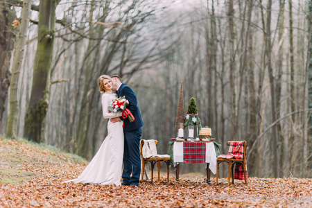 Wedding couple near the decorated table for Christmas holidays in autumn forestの写真素材
