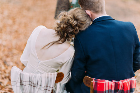 Wedding couple sitting and hugging at the holiday table in autumn forest.