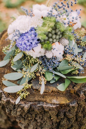 Beautiful wedding bouquet of colorful spring flowers on the stump in forest.の写真素材