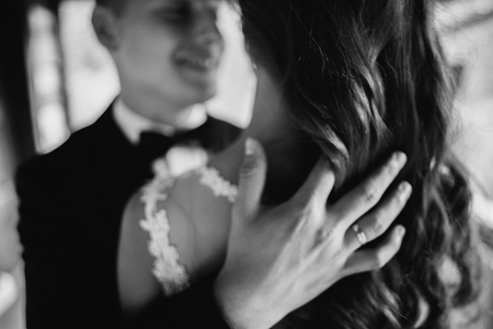 Black and white close up portrait of handsome young groom embracing his wife.の写真素材