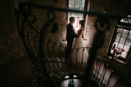 Young married couple standing face to face at the stairs and holding hands.の写真素材