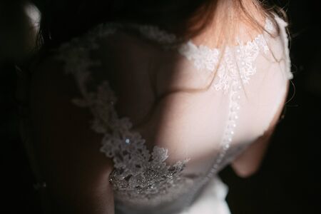 A close up of the bride's back in white wedding dress.の写真素材