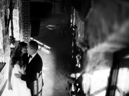 Beautiful young married couple standing by window embracing face-to-face.の写真素材