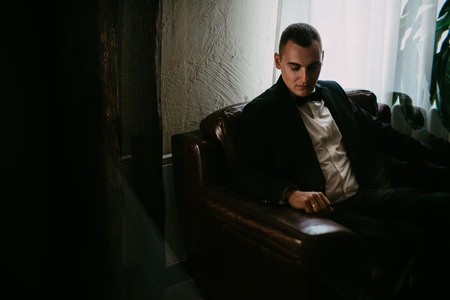 A portrait of young man sitting in the chair and looking down.の写真素材
