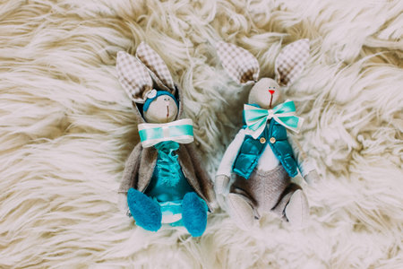 Two cute toy bunnies in bow-ties on white background.