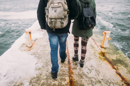 Happy stylish couple walking on the old pier in winter vacation. Travel together concept. Sea background.の写真素材