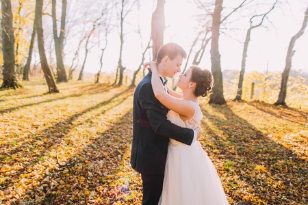 Smiling couple hugging  in autumn park. Happy bride and groom in forest, outdoorsの写真素材