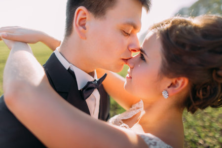 Cute romantic wedding couple, bride and groom, hugging in rye field at sunsetの写真素材