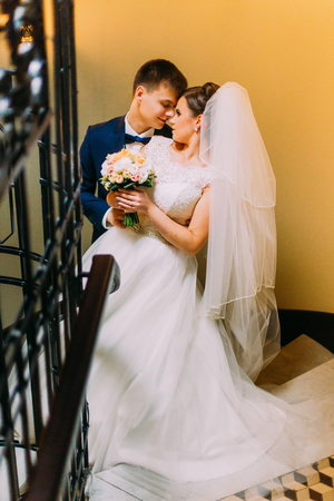 Newly young married couple embracing face-to-face standing at the stairs.の写真素材