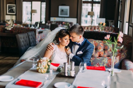 Portrait of a beautiful embracing couple  in vintage cafe. Wedding day. Close up. Indoor shot.の写真素材