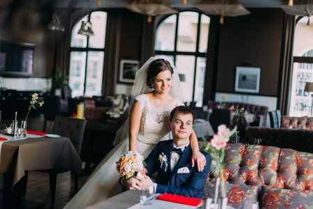 Happy smiling bride hugging groom from back at restaurant.の写真素材