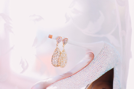 Female wedding accessories golden earrings over white veil background.の写真素材